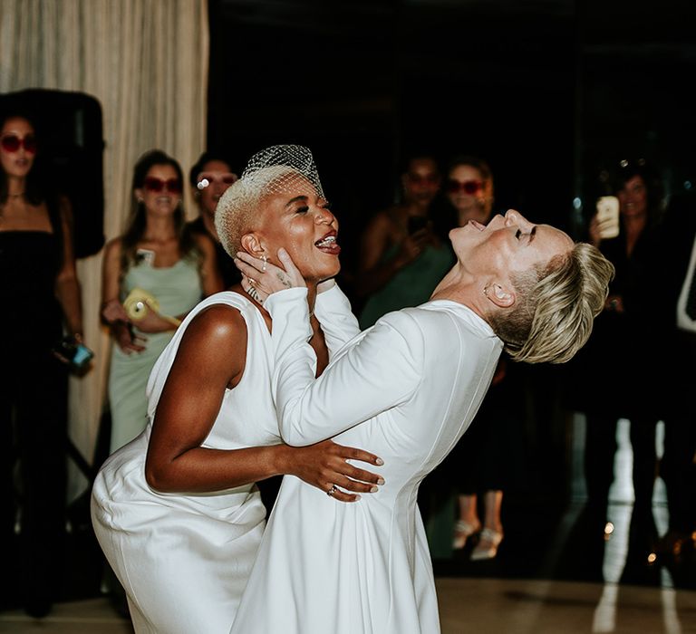 Two brides in their wedding reception outfits have first dance together 