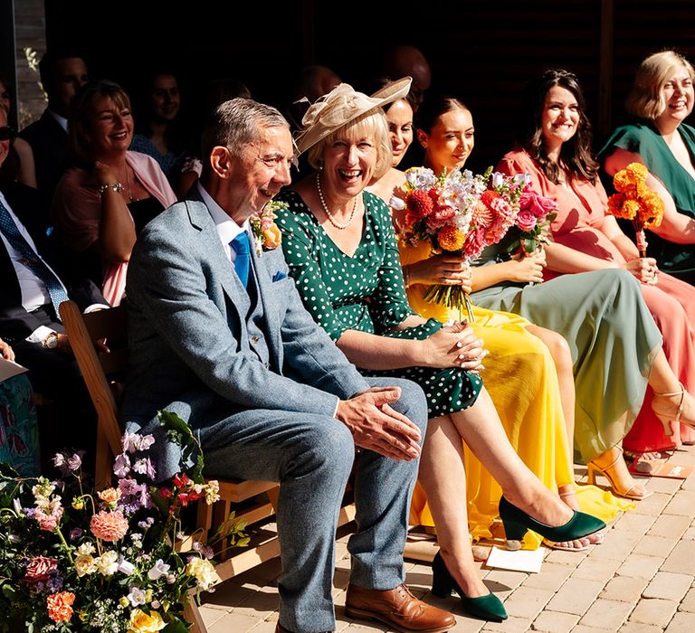 Wedding guests wearing colourful dresses and suits at colourful outdoor wedding 