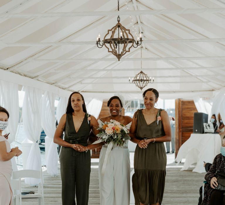 Same sex wedding ceremony bridal entrance with her sisters in olive green dresses