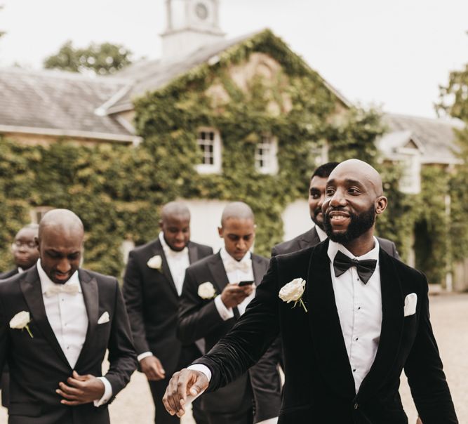 Black groom in a black velvet tuxedo jacket with his groomsmen 