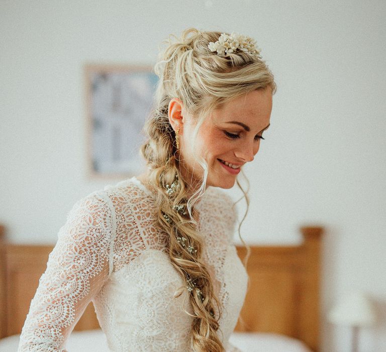 Blonde bride with long plaited hair to the side, complete with a flower crown and wearing lace wedding gown