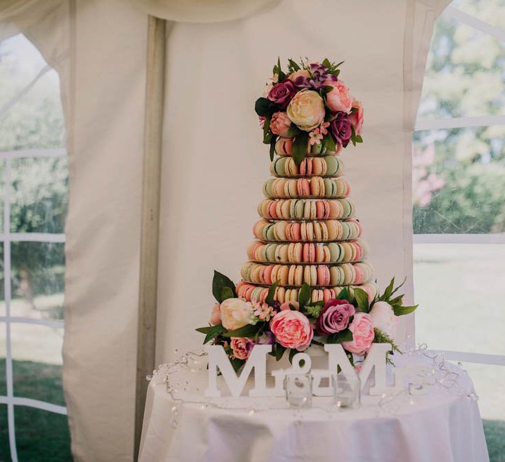 Multicoloured macaroon tower on table in marquee with 'mr & mrs' signage in front