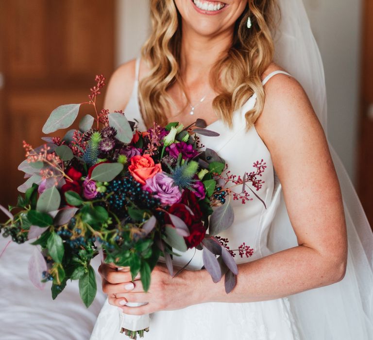 Blonde haired bride smiles with pink floral bouquet 