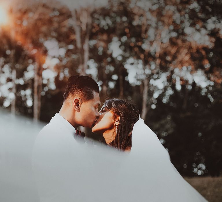 Bride & groom kiss outdoors after wedding ceremony