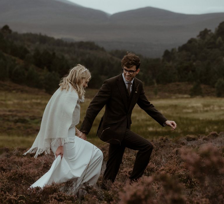 Bride & groom walk through the hills together during wedding day