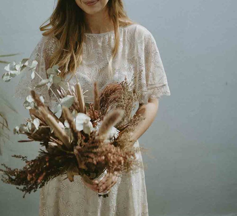 Bride clutches dried wedding bouquet