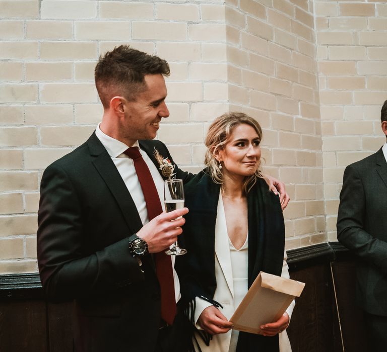 Bride & groom stand together and listen to speeches on the day of their wedding