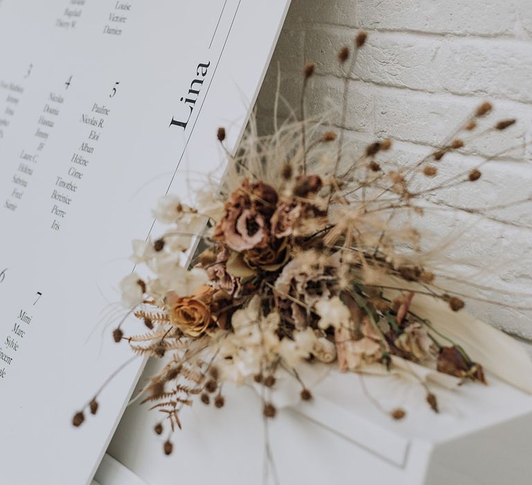 Dried flowers and minimal white seating plan sign for all white wedding shoot