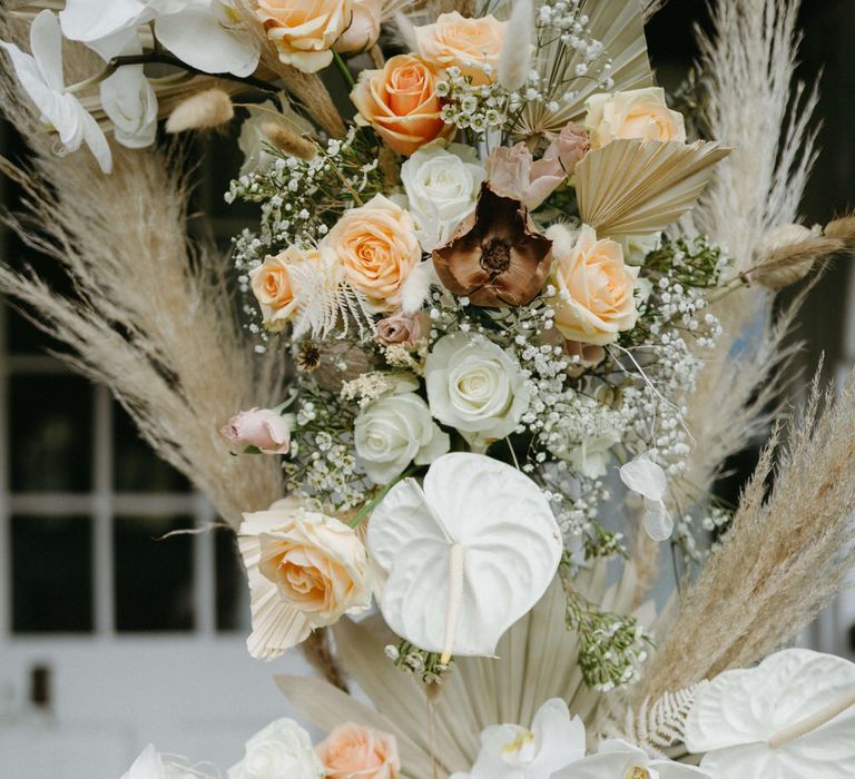 Flower arch detail of dried palms, pampas grass, white anthuriums, roses and orchids