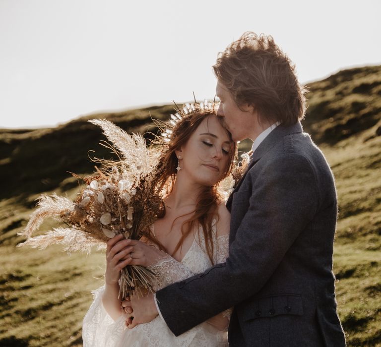 Bride leans head into groom as the sun shines behind them