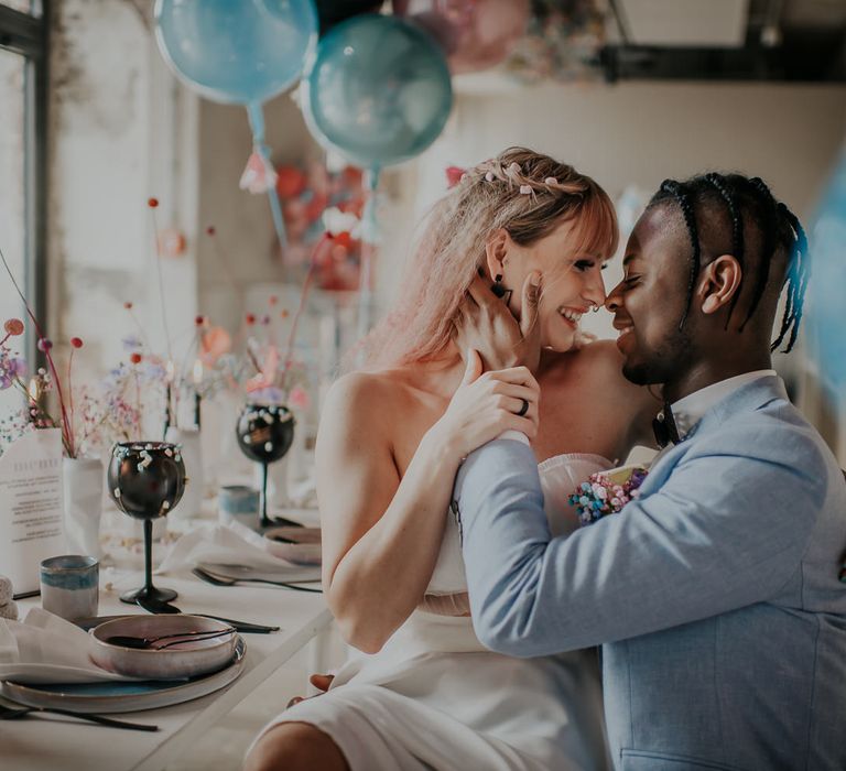 Bride and groom sitting at the wedding breakfast table decorated with pastel flowers and decor 