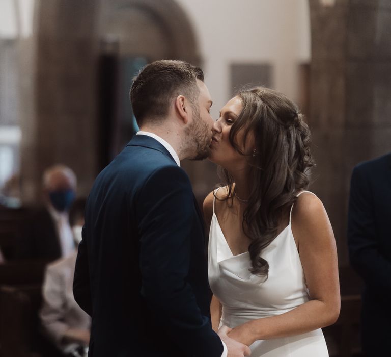 Bride and groom kiss as they get married in their local church