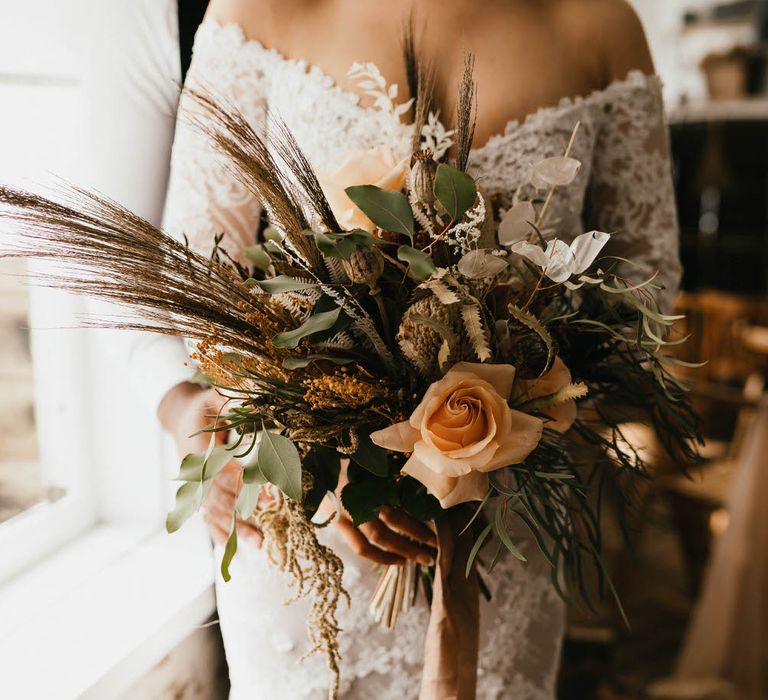 Large bridal bouquet of peach coloured roses with foliage and wild grasses