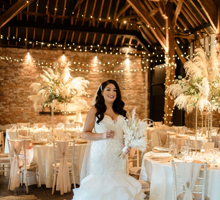 Bride in a strapless lace wedding dress with fishtail skirt standing in the wedding reception at Cooling Castle Barn 