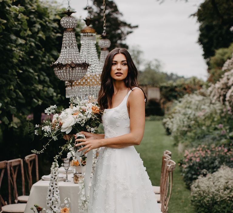 Bride with long wavy hair in at an elegant outdoor wedding reception in an appliqué Suzanne Neville bridal gown from the new Nova 2022 bridal collection 