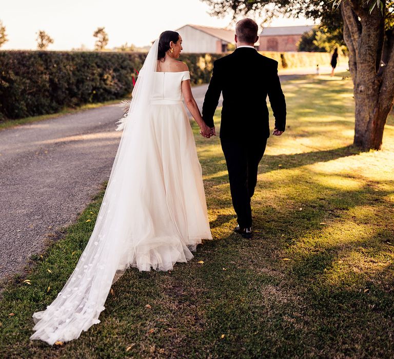 Bride in off the shoulder wedding dress with petal detail veil