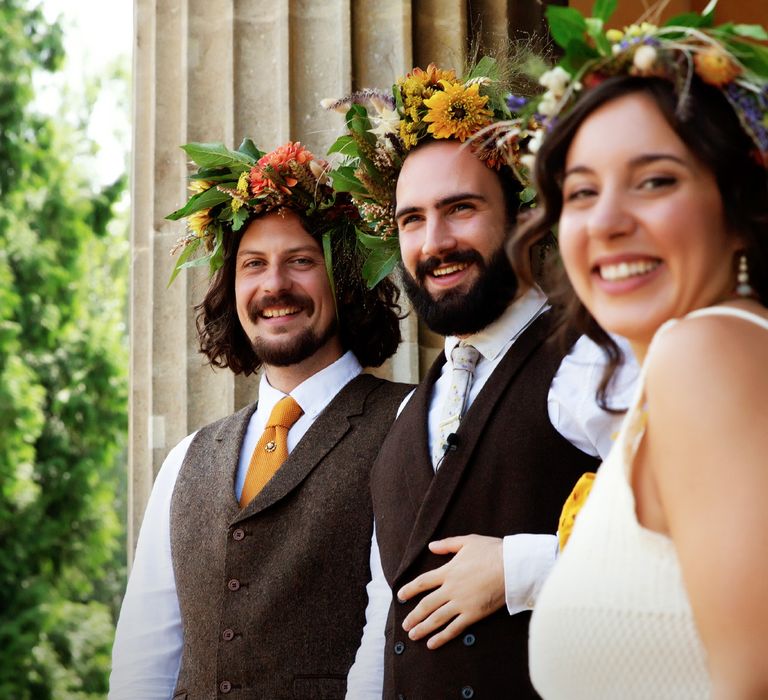 Grooms stand and smile with one another and wedding guest