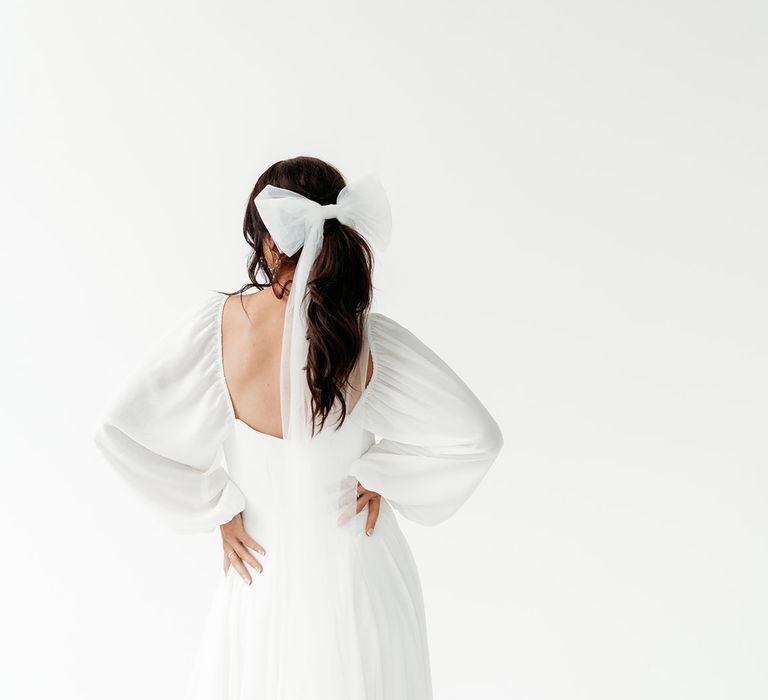 Bride in a floaty wedding dress with blouson sleeves in a long bridal bow headdress 