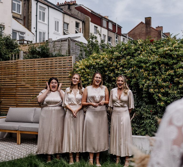 Bridesmaids in champagne dresses see bride for the first time in her dress