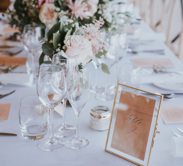 White wedding tablescape with pink and white florals, glassware, gold frame table numbers and candles for summer wedding at Primrose Hill Farm