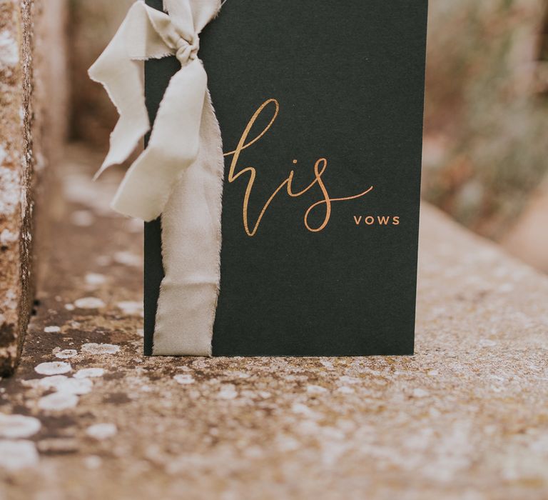 Dark green vow booklet with gold calligraphy and white ribbon for outdoor wedding ceremony