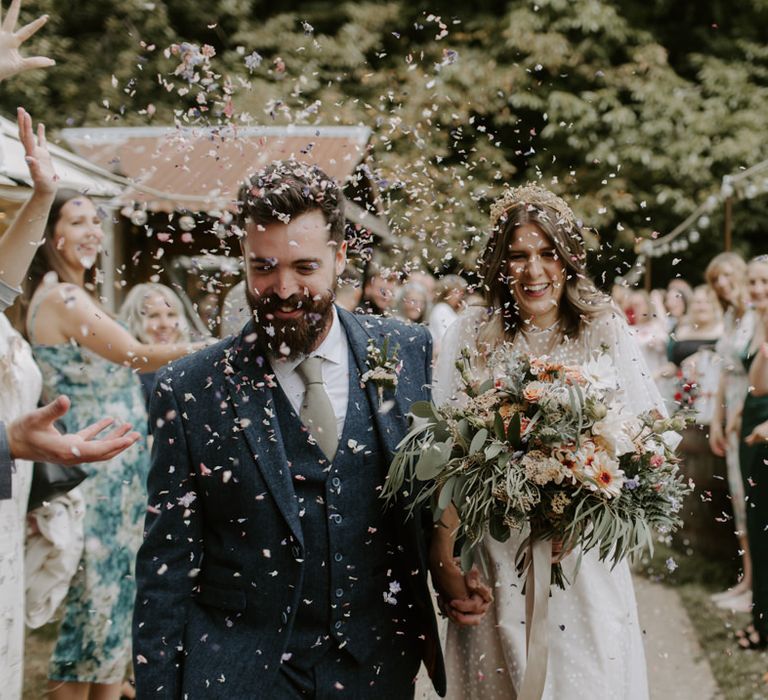 Bride wears E&W Couture wedding gown whilst holding floral bouquet 