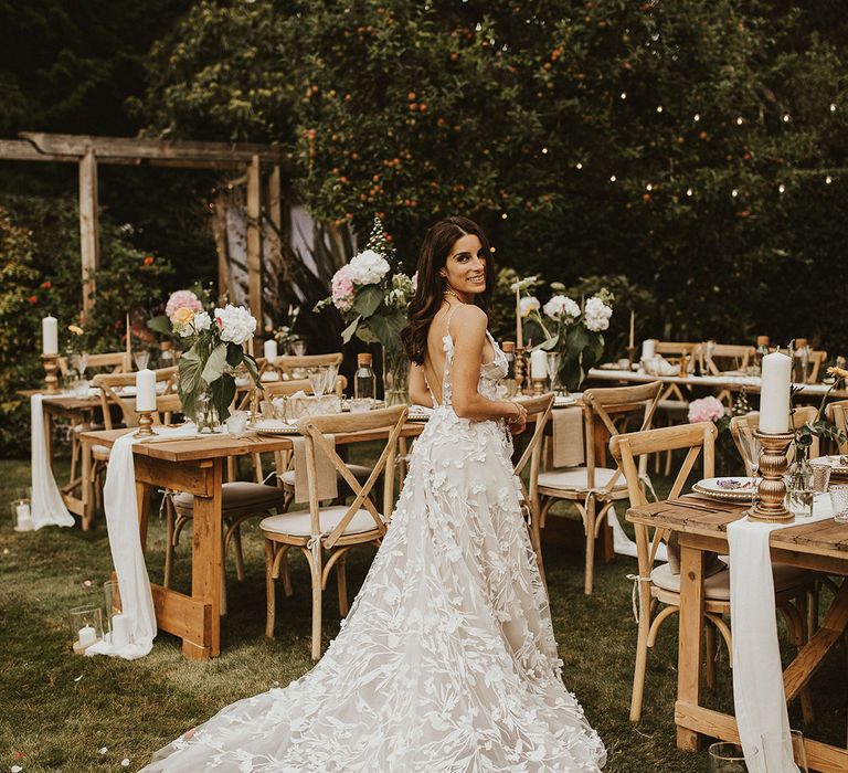 Bride stands beside table on her wedding day wearing Alena Leena Bridal gown