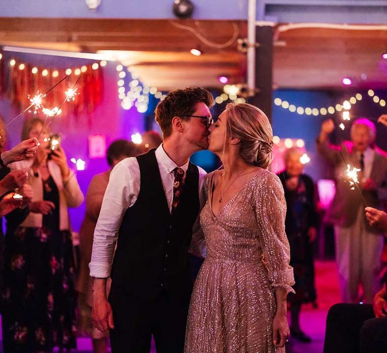 Bride & groom kiss as brightly coloured lights shine around them