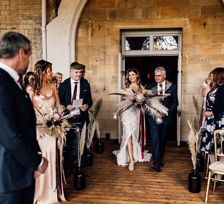 Bride walks with her father into wedding ceremony on her wedding day