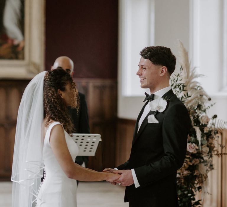 Bride & groom hold hands as they look lovingly at one another