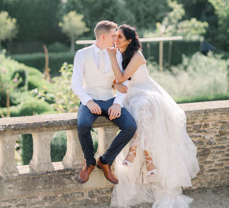 Bride & groom kiss outdoors in front of gardens on their wedding day