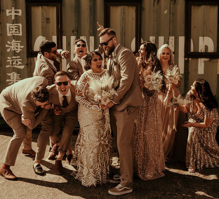 Fun wedding party photography at industrial wedding with groomsmen in tweed suits, bridesmaids in blush gowns and the bride in a boho wedding dress 