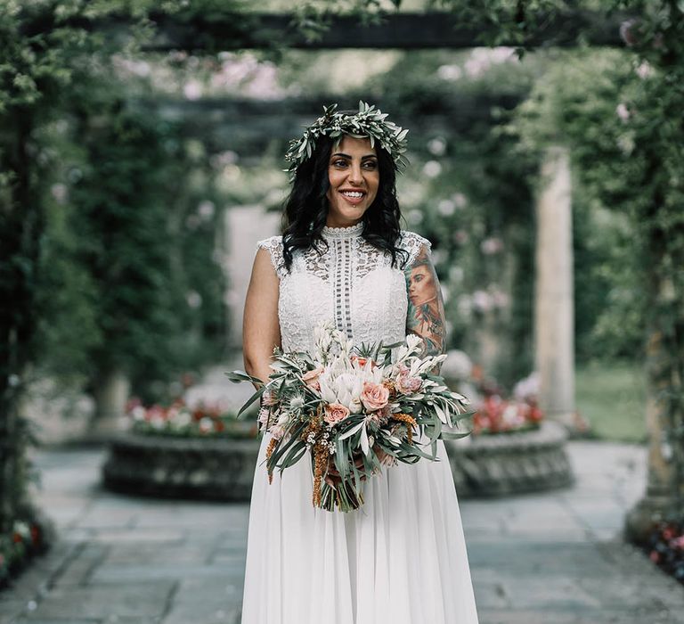 Bride wears floral crown complete with boho chic lace wedding gown with high neck and capped sleeves 