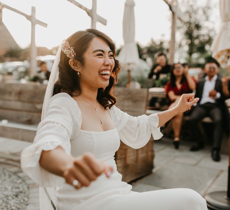 Smiling bride in white square neckline wedding dress with puff sleeves and dainty pearl earrings 