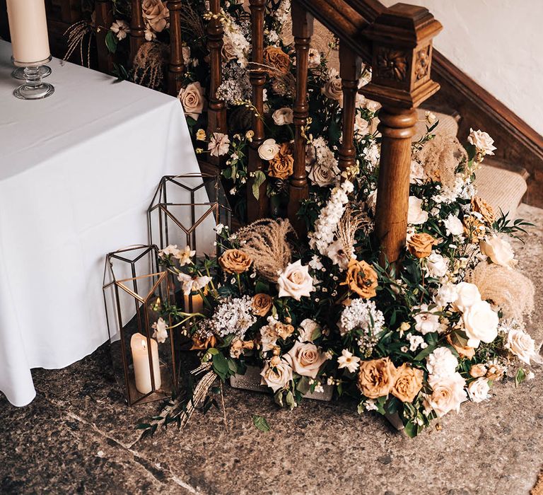 Toffee roses, beige, rust, pink and white flowers with dried flowers for wedding decor with large lanterns for candles on the stairs 