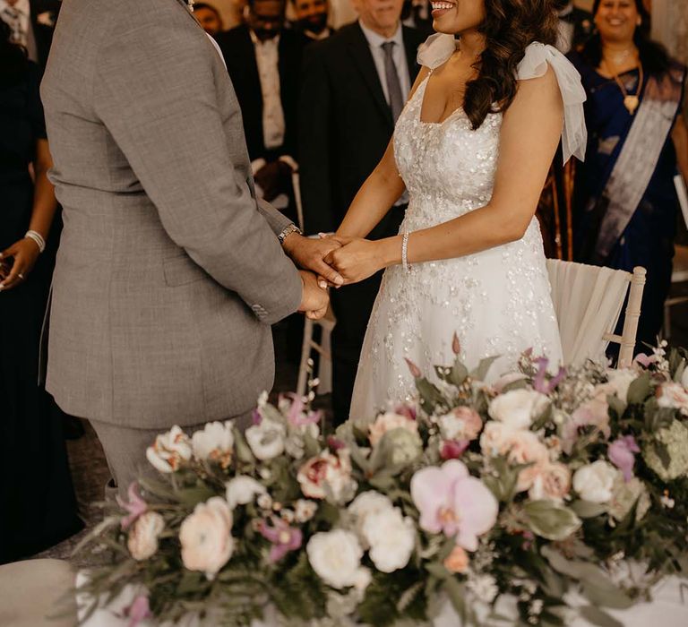 Bride and groom at the alter, holding hands and smiling