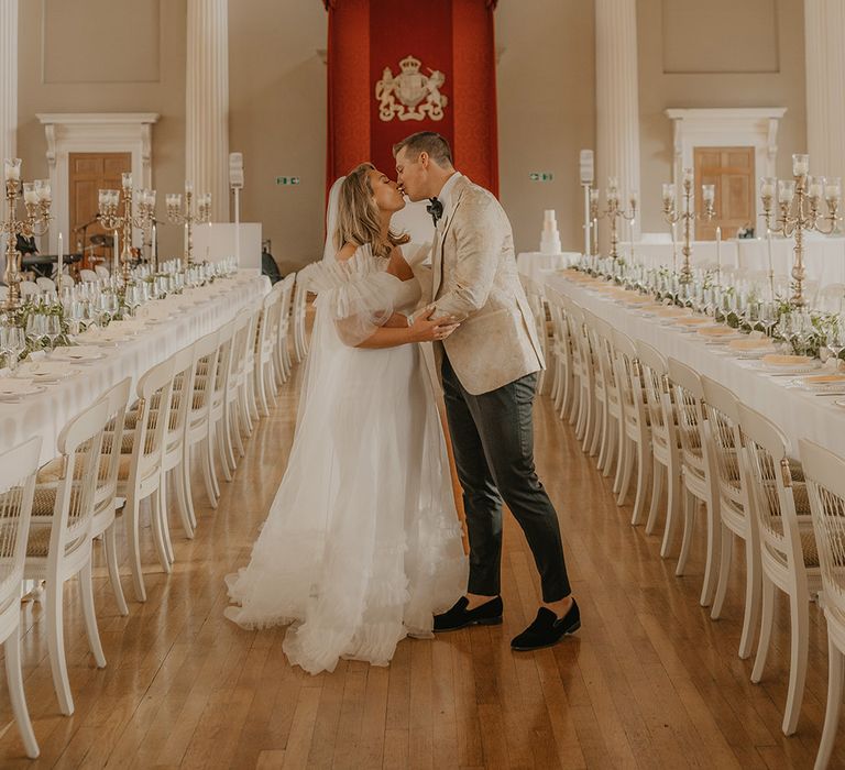 Bride and groom share a kiss in the gorgeous Banqueting House in London with gold decor including chandeliers and candelabras