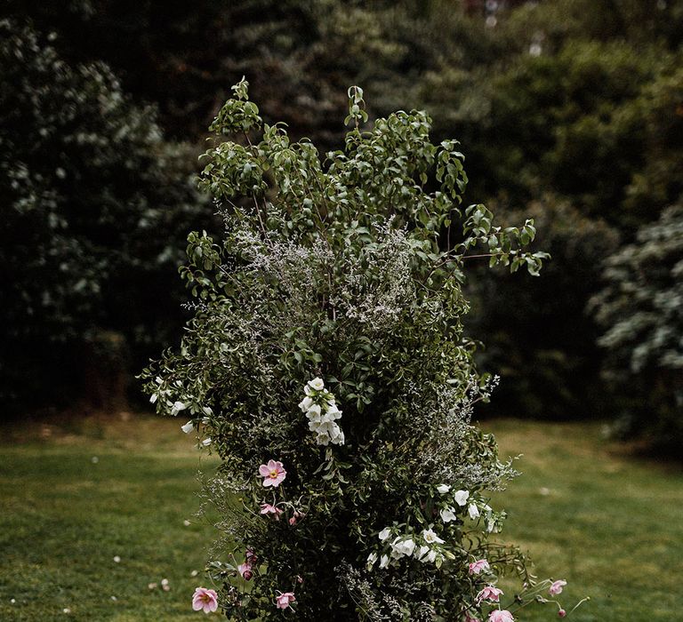 Tall flower column for altar decor with lots of greenery and white bell flowers and pink cosmos 