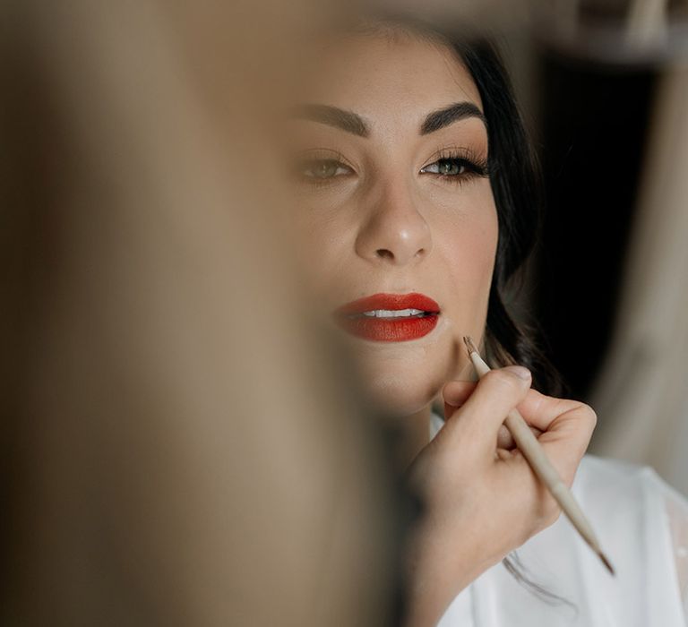 Bride gets her makeup done with a bright red lipstick 