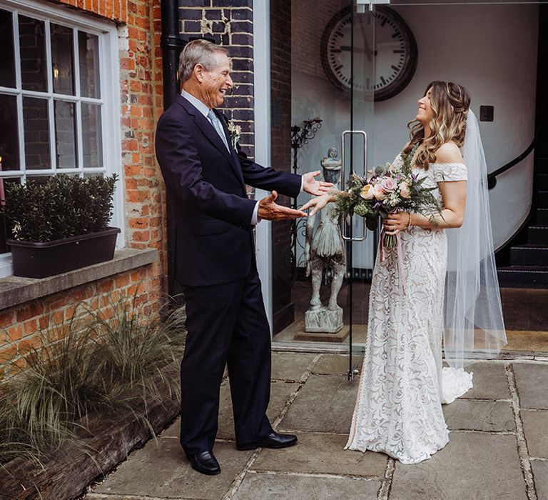 Father of the bride in a blue suit gets a first look at the bride in her off the shoulder lace wedding dress 