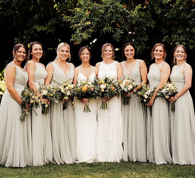 Brides stand with their bridesmaids in soft green dresses