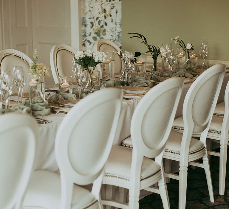 Sage green and white wedding tablescape with gold details, floating tea lights and faux wedding flowers 