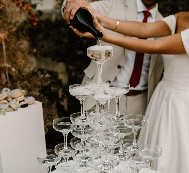 Champagne tower with the bride and groom pouring the champagne