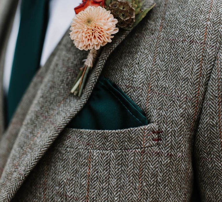 Groom in a grey tweed suit with a dark forest green tie and pocket square and a pink and red flower buttonhole 