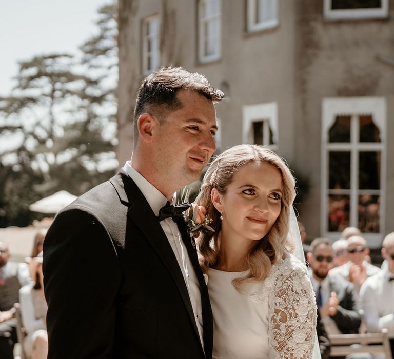 The happy couple stand smiling at their wedding celebrant as they are officially married 