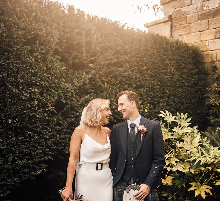 Bride & groom walk alongside one another during golden hour portraits outdoors 