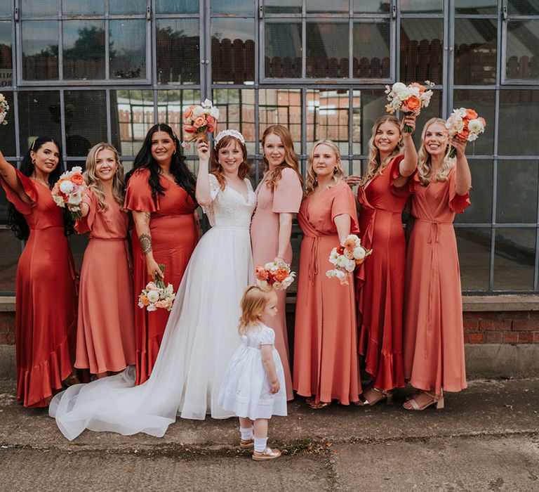 The bride with the flower girl and bridesmaids in coral peach bridesmaid dresses 