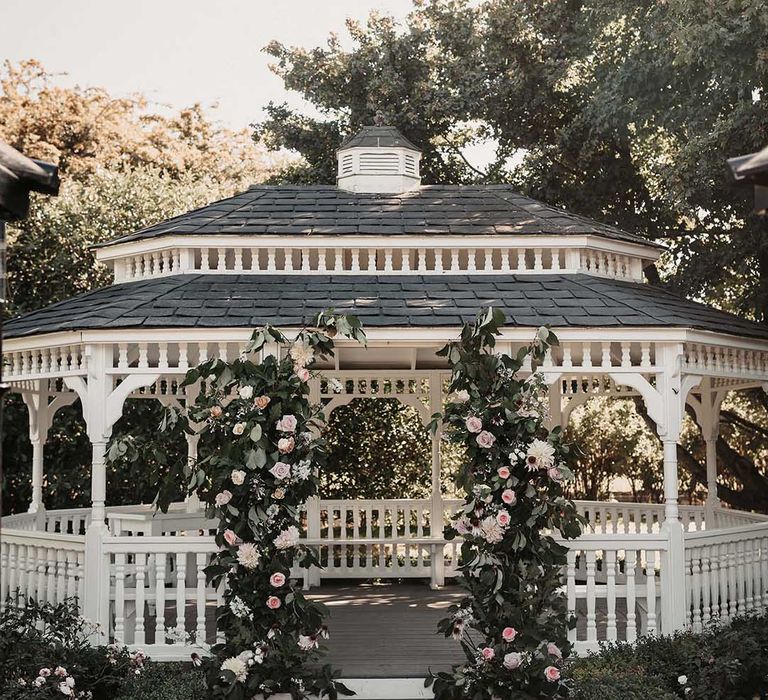 White bandstand with white and light pink garden rose and foliage columns at Old Kent Barn