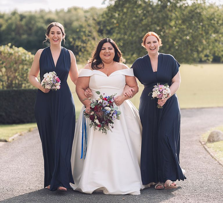 Midnight blue bridesmaid dresses in silk fabric and different styles with the bride in an off the shoulder Essense of Australia wedding dress 