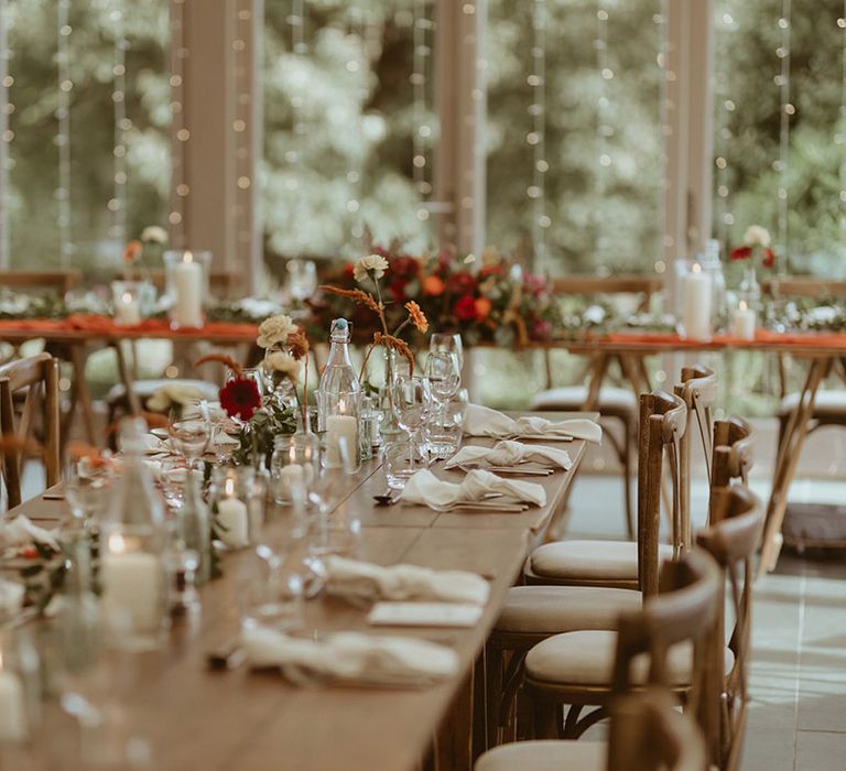 Cosy autumn wedding with fairy lights, candles and warm toned orange wedding flower arrangements at Trevenna Barns in Cornwall 